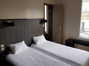 2 camas individuales en una habitación con ventana en Hôtel D'Anjou, en Levallois-Perret