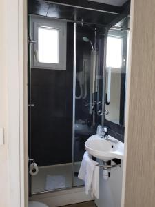 a bathroom with a glass shower and a sink at Hôtel D'Anjou in Levallois-Perret