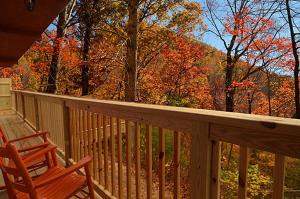 a wooden deck with a rocking chair and autumn leaves at #820 Honeymoon Hideaway in Gatlinburg