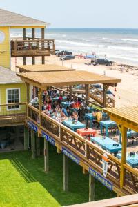 a beach restaurant with people sitting at tables and a beach at Ocean Village Hotel in Surfside Beach