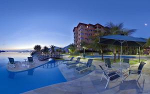 een zwembad met stoelen en tafels en een parasol bij Porto Bali - Resort Mercure in Angra dos Reis