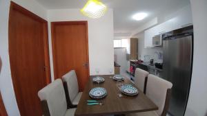 a kitchen with a wooden table with chairs and a refrigerator at Condomínio Residencial Tranquilidade na Beira do Rio in Paulo Afonso