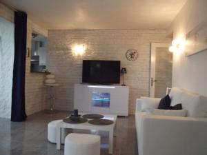 ein Wohnzimmer mit einem weißen Sofa und einem TV in der Unterkunft LE BELVEDERE 1- Front de Mer - Plage Argelès in Argelès-sur-Mer