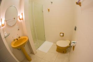 y baño con ducha, aseo y lavamanos. en Hotel Itajara, en Jaraguá do Sul