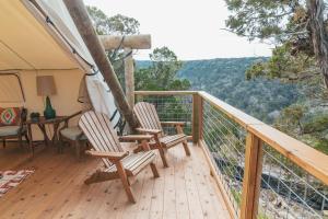 a porch with two chairs and a table on a deck at Collective Hill Country in Wimberley