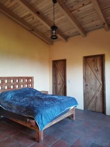 マサミトラにあるCABAÑAS COLINAS de SAN NICANORの青い掛け布団と2つのドアが付いたベッドのある寝室