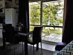 mesa de comedor con sillas frente a una ventana en Down South Cottage en Invercargill