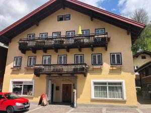 ein Gebäude mit einem Balkon und einem vor der Unterkunft geparkt roten Auto in der Unterkunft Pension Reiterhaus in Wagrain