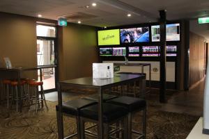a bar with stools and televisions on a wall at Royal Hotel Orange in Orange