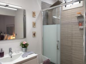 ein weißes Bad mit einer Dusche und einem Waschbecken in der Unterkunft Apartamento Plaza San Marcos in Icod de los Vinos