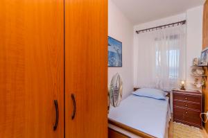 a bedroom with a bed and a wooden cabinet at Apartment Buksa in Trogir