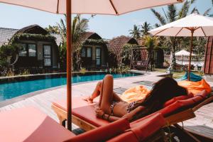 a woman laying on a lounge chair next to a pool at Papa Sun Villas in Nusa Penida