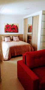 1 dormitorio con 1 cama y 1 sofá rojo en Flats Dunas Cabo Frio, en Cabo Frío