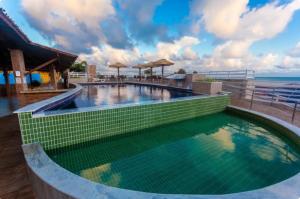 a swimming pool in a resort with a view of the ocean at Pipas Bay - FLAT BEIRA MAR in Pipa