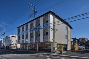 ein großes weißes Gebäude in einer Stadtstraße in der Unterkunft HOTEL ARROWS ARASHIYAMA in Kyoto