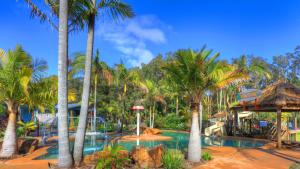 ein Resortpool mit Palmen und Rutsche in der Unterkunft BIG4 Bays Holiday Park in Anna Bay