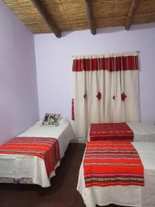 - une chambre avec 2 lits et une fenêtre avec des rideaux dans l'établissement La Posada de Bartola, à Tilcara