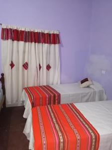 um quarto com duas camas e uma cortina em La Posada de Bartola em Tilcara