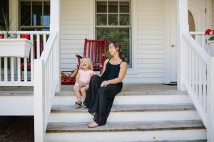 a woman and a child sitting on the steps of a house at Eagle Harbor Inn in Ephraim