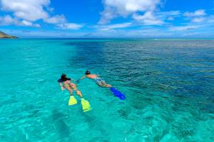 Oarsman's Bay Lodge في Nacula Island: شخصان يسبحان في الماء في المحيط