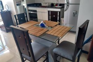a glass table with two chairs and a kitchen at Hermoso y acogedor apartamento en Belén Rodeo Alto in Medellín