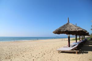 eine Reihe von Liegestühlen und einem Sonnenschirm am Strand in der Unterkunft Sandunes Beach Resort & Spa in Mui Ne