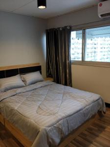 a bedroom with a large bed with a window at Popular Condo เมืองทองธานี in Pak Kret