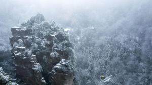una persona parada en la cima de una montaña rocosa en Oh! Hotel - Nordic Style Hotel en Zhangjiajie