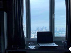 Modern Place of Style في مانيلا: يوجد جهاز كمبيوتر محمول على مكتب أمام النافذة