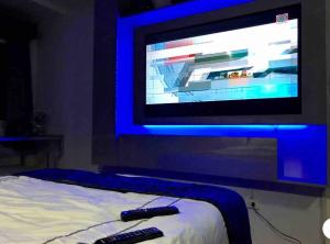 twee afstandsbedieningen zittend op een bed voor een tv bij Modern Place of Style in Manilla