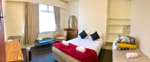 Habitación de hotel con cama y silla en Harbourview Stadium Hotel, en Dunedin