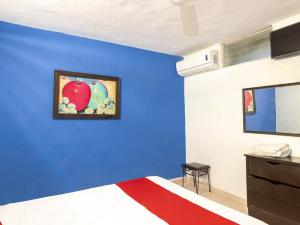 a bedroom with a blue wall with a bed and a painting of an apple at Hotel Aventura in Mérida