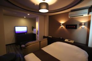 um quarto de hotel com uma cama e uma televisão em Hotel Sindbad Hirosaki-Adult Only em Hirosaki