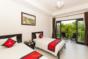 Una habitación de hotel con dos camas y balcón. en Hoi An Hideaway Villa, en Hoi An
