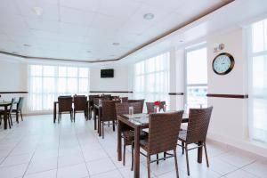 una sala da pranzo con tavoli, sedie e orologio di Mayfair Hotel a Dar es Salaam