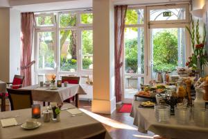 un comedor con mesas, sillas y ventanas en Stadthaushotel Hamburg - Inklusionshotel, en Hamburgo