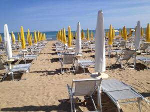 uma fila de cadeiras e guarda-sóis numa praia em Ute Hotel em Lido di Jesolo