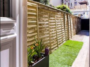 un jardín con una valla de madera y césped verde en LE REFUGE avec terrasse et jardin, en plein centre-ville, gare 5 minutes à pieds, en Niza