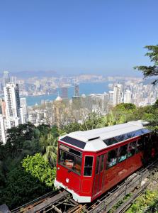 a red train traveling down the tracks in front of a city at Kew Green Hotel Wanchai Hong Kong in Hong Kong +33 photos
