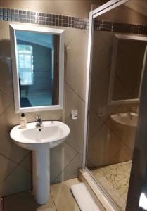 uma casa de banho com um lavatório, um espelho e um chuveiro em Garsfontein Bed and Breakfast em Pretoria