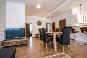 a dining room with a table and chairs and a television at Fogra Travel Apartment in Krakow