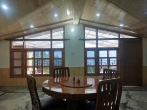 einen Holztisch und Stühle in einem Zimmer mit Fenstern in der Unterkunft Vipul Home Stay in Shimla
