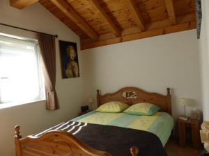 a bedroom with a bed with a wooden headboard and a window at B&B Les Acacias in Le Châble