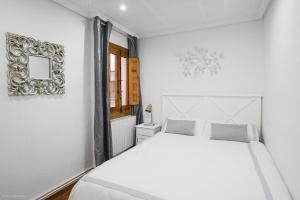 a white bedroom with a white bed and a mirror at Apartamento LA CATEDRAL CUENCA in Cuenca