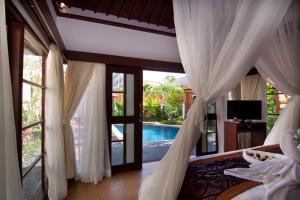 a bedroom with a bed and a view of a pool at The Awan Villas - CHSE Certified in Seminyak