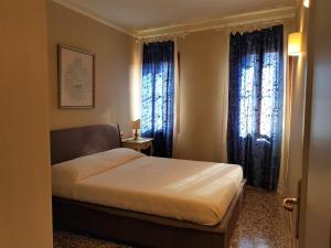 ein Schlafzimmer mit einem Bett und zwei Fenstern in der Unterkunft Cà Melidissa in Venedig