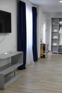 a living room with a tv and blue curtains at Del Mare семейный корпус in Kapchagay