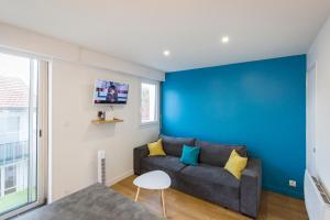 a living room with a couch and a blue wall at LOURDES cosy appartement sanctuaire centre ville in Lourdes