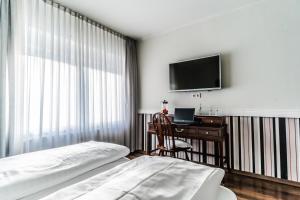 a bedroom with a bed and a desk and a television at Privathotel Stickdorn in Bad Oeynhausen