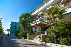 a hotel on the side of a street with palm trees at Hotel Janeiro in Caorle